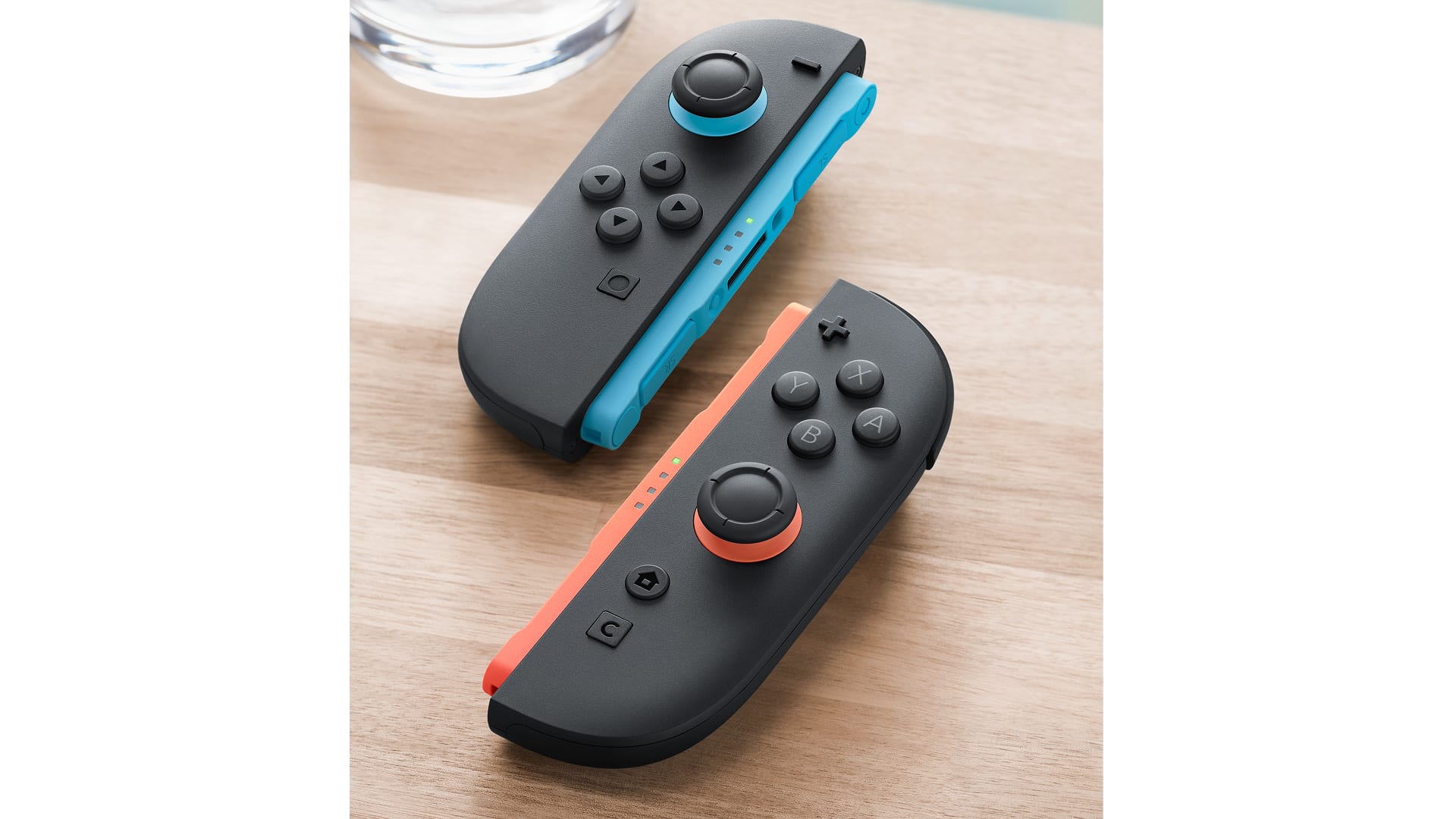 Two Nintendo Switch 2 Joy-Con 2 controllers lying on their sides on a wooden table, positioned for mouse mode