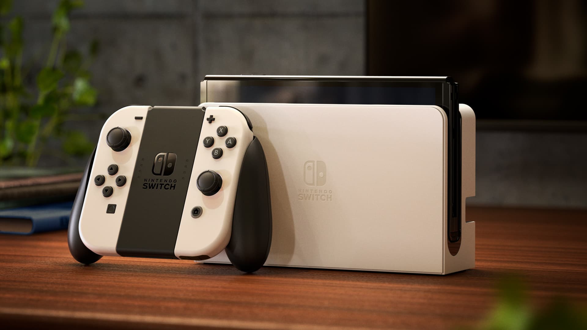 Nintendo Switch – OLED Model console in its dock with white Joy-Con controllers attached, on a wooden table