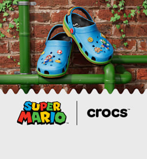 Super Mario Core Classic Clogs feature a blue colorway with a graphic print including coins, Super Stars, and Green Shells. Jibbitz charms include Mario and Luigi.