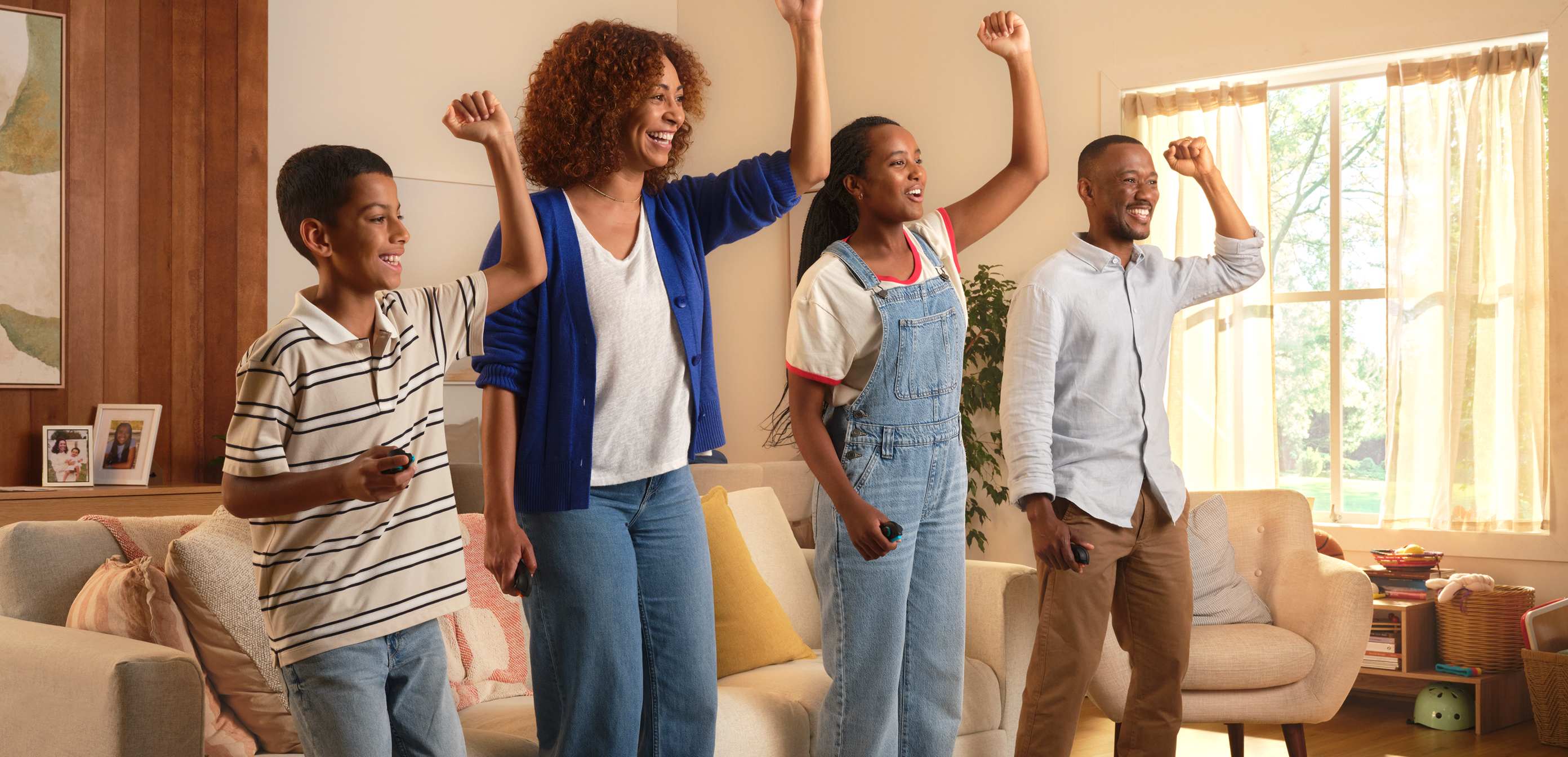 All smiles, a family of four each pumps their left arm in the air.