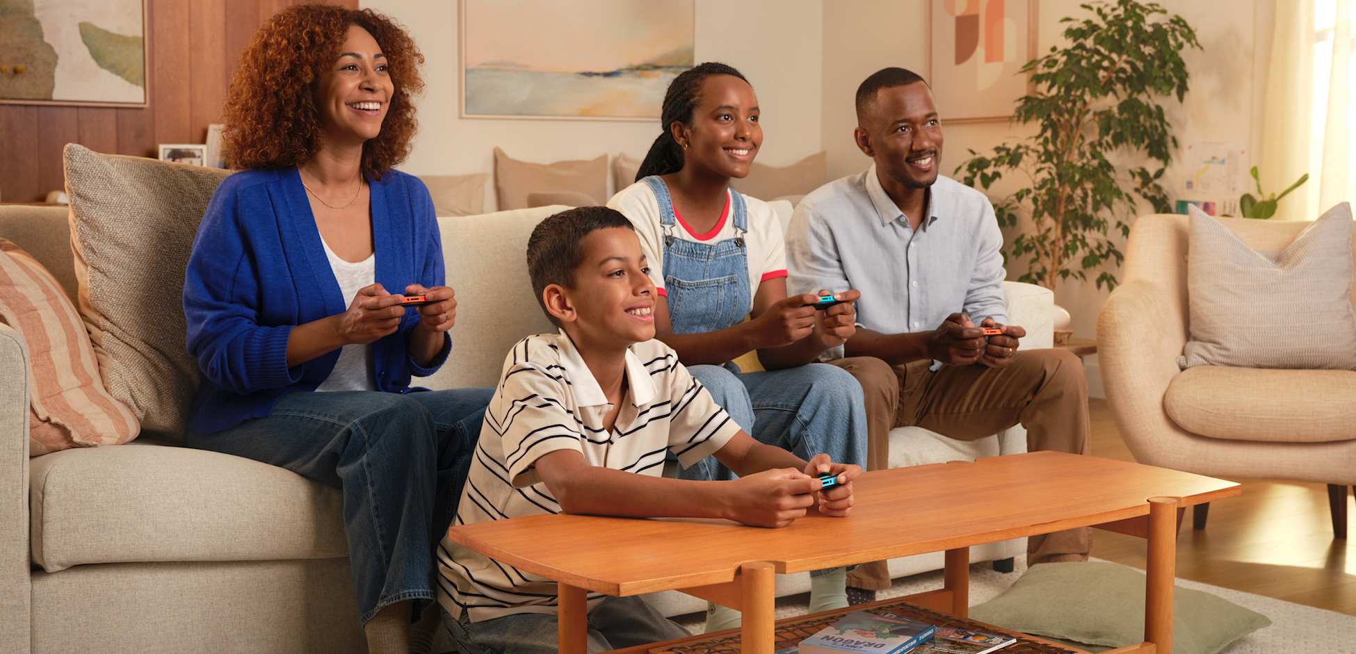A family of four smiles as they play Nintendo Switch 2 in TV mode.