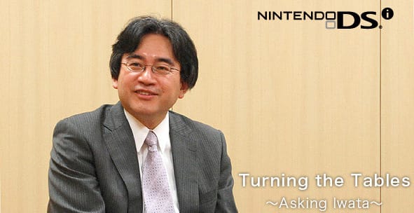 Foto von Satoru Iwata, ehemaliger Nintendo-Präsident, der maßgeblich an der Entwicklung des Nintendo DS beteiligt war. Er trägt einen grauen Anzug und lächelt, während er in einem Interview spricht. Im Hintergrund das Nintendo DS-Logo und der Schriftzug „Asking Iwata“.