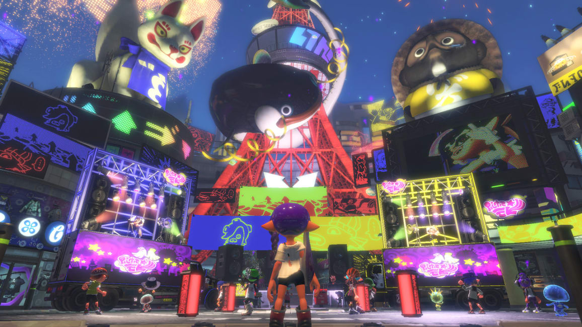 Inkopolis Plaza at night during a Splatfest. The city is vibrant with neon player artwork. Callie and Marie perform on individual stages on the left and right sides of the plaza.